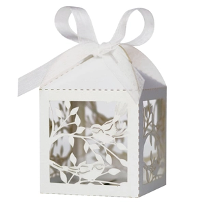 Close-up of white laser-cut bird and branch patterns on an elegant wedding candy box