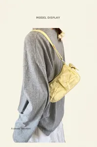 Détail des poches à nœuds papillon crème sur un sac en cuir verni brillant pour femme