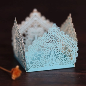 Macro detail of laser-cut light blue cardstock wedding candy box with lace pattern