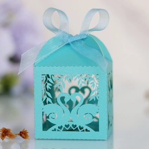 Close-up of laser-cut light blue candy box with swan heart design and ribbon decoration