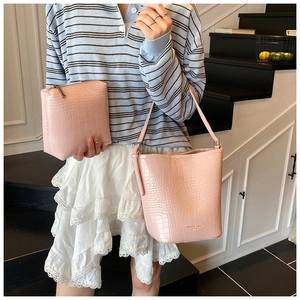 Pink crocodile pattern bucket bag and clutch set shown by model in a daily scene