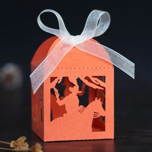 Close-up of laser-cut orange favor box with cowboy horse silhouette and white ribbon bow