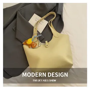 Detail of yellow lychee leather tote bag with elephant charm on a stylish background