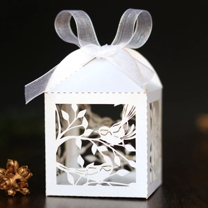 Detail of laser-cut love bird paper candy box with elegant white ribbon and bow decoration