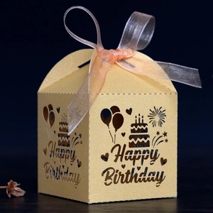 Gros plan d'une boîte cadeau dorée découpée au laser avec ruban en mousseline rose