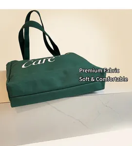 Dettaglio della borsa tote in tela verde scuro con scritta Care e tracolla robusta e rifinita