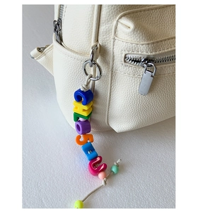 Détail d'une breloque en perles colorées sur un sac à dos blanc en cuir grainé