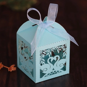 Detail of light blue laser-cut swan candy box with elegant ribbon bow on wood surface