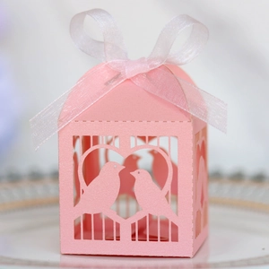 Détail d'une boîte à dragées rose découpée au laser avec des oiseaux et ruban blanc