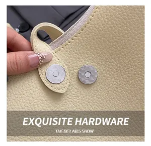 Macro detail of silver magnetic snap button on beige lychee leather tote bag