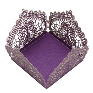 Close-up of laser-cut hollow lace patterns on a deep purple wedding decorative candy box