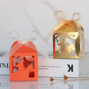 Macro view of laser-cut party favor boxes with cowboy silhouette and ribbon bow
