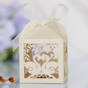 Close-up of laser-cut cream swan wedding favor box with a delicate white ribbon bow