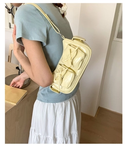 Détail du sac crème avec poches à nœuds et finition en cuir brillant élégant