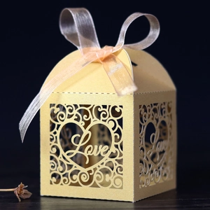 Detailed view of golden laser-cut wedding favor box with LOVE motif and ribbon
