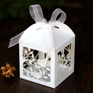 Close-up of white laser-cut bird pattern candy box with a soft ribbon bow and handle