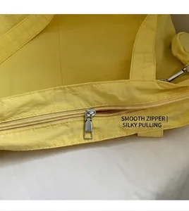 Close-up of smooth metal zipper detail on yellow nylon tote bag with textured fabric