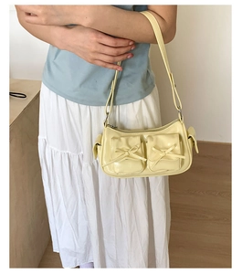 Détail du sac sous l'aisselle jaune clair avec poches à nœuds décoratifs et fini brillant