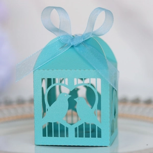 Détail de boîte à bonbons bleu clair découpée au laser avec motif d'oiseaux et ruban