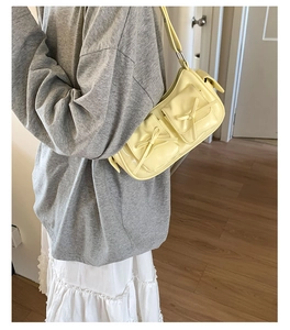 Détail du sac jaune à nœuds et poches latérales porté avec une tenue décontractée