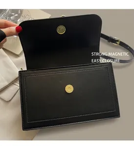 Detail of black leather flap bag showing the strong gold magnetic buckle and closure
