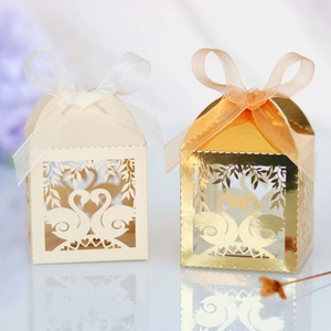 Detail of laser-cut white and gold swan candy boxes with elegant organza ribbons
