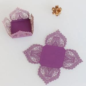 Macro detail of laser-cut purple gift box showing intricate lace patterns and folding