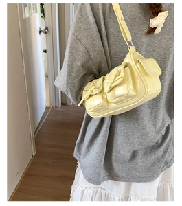 Détail du sac à bandoulière jaune clair avec poches à nœuds élégantes et finition brillante