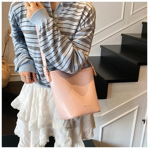 Close-up of pink faux leather bucket bag with crocodile texture and fashion logo details