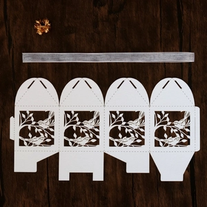 Flat lay macro of laser cut bird pattern gift box with silver ribbon and gold flower