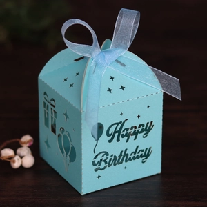 Close-up of light blue hollow-out Happy Birthday gift box with ribbon on wood