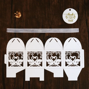 Detail of white laser-cut swan gift box with grey ribbon and thank you tag on wood