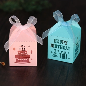 Detail of pink and blue house-shaped laser cut birthday candy boxes with organza ribbons