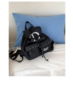 Detail of black canvas backpack showing silver metal studs and printed lettering