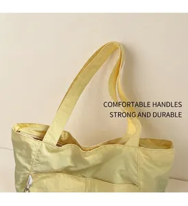 Detail of light yellow waterproof nylon tote bag showing comfortable strap and side pocket