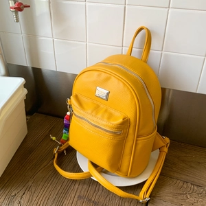 Détail d'un mini sac à dos en cuir jaune vif à texture litchi avec plaque métallique