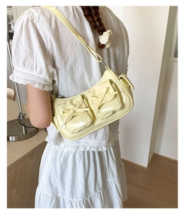 Détail du sac à bandoulière en cuir verni jaune clair avec nœud doux et double poches