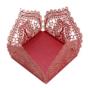 Detail of red laser-cut candy box featuring intricate floral lace patterns for weddings
