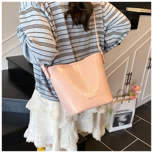Detail of pink faux leather bucket bag with crocodile embossed texture and strap