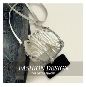 Close-up of white woven bucket bag with tassel drawstring and silver chain strap details