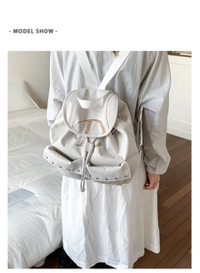 Gros plan d'un sac à dos blanc avec rabat, cordon de serrage, lettre D brune et rivets décoratifs