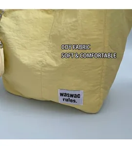 Detail of yellow tote bag showing smooth fabric texture and woven brand label