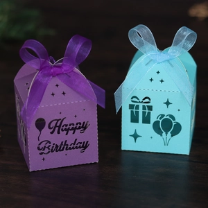 Detail of laser-cut Happy Birthday gift boxes in purple and teal with satin ribbons