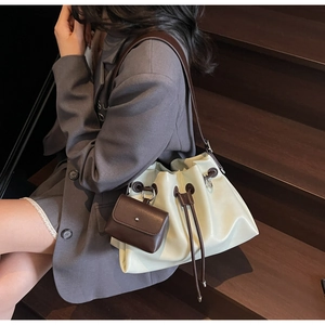 Detail of cream and brown contrast bucket bag with drawstring closure and small pouch