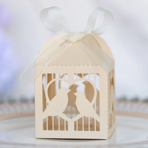 Détail de boîte à dragées ivoire découpée au laser avec motif oiseaux et ruban en organza