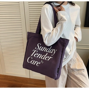 Dettaglio della borsa tote in tela viola con scritta artistica Sunday Tender Care bianca