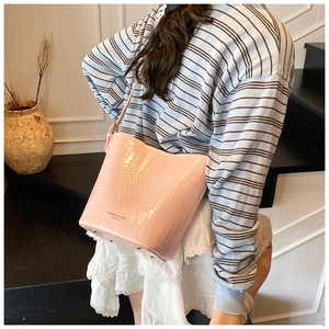 Pink crocodile pattern bucket bag shown in use with adjustable shoulder strap
