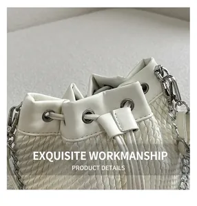 Detailed macro of white bucket bag showing woven texture and silver chain strap detail