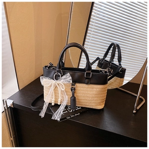 Detail of the woven straw handbag featuring a large lace pearl bow and leather trim