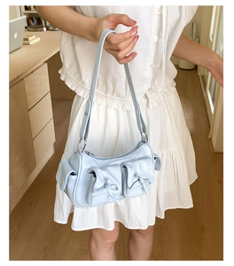 Détail du sac à main bleu clair avec nœuds, poches et bandoulière réglable en cuir